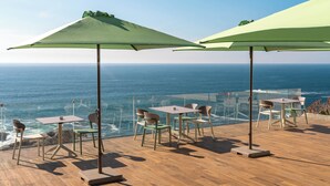 A terrace with tables and chairs overlooking the ocean. - HOTEL BOUTIQUE FARO SILLEIRO (Baiona)