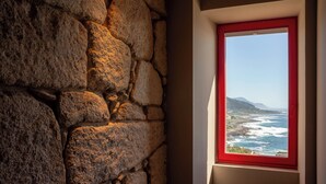 A stone wall with a window overlooking a coastal view. - HOTEL BOUTIQUE FARO SILLEIRO (Baiona)