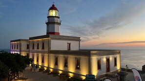 A lighthouse with a white and red exterior, a light at the top, and a view of the sea. - HOTEL BOUTIQUE FARO SILLEIRO (Baiona)
