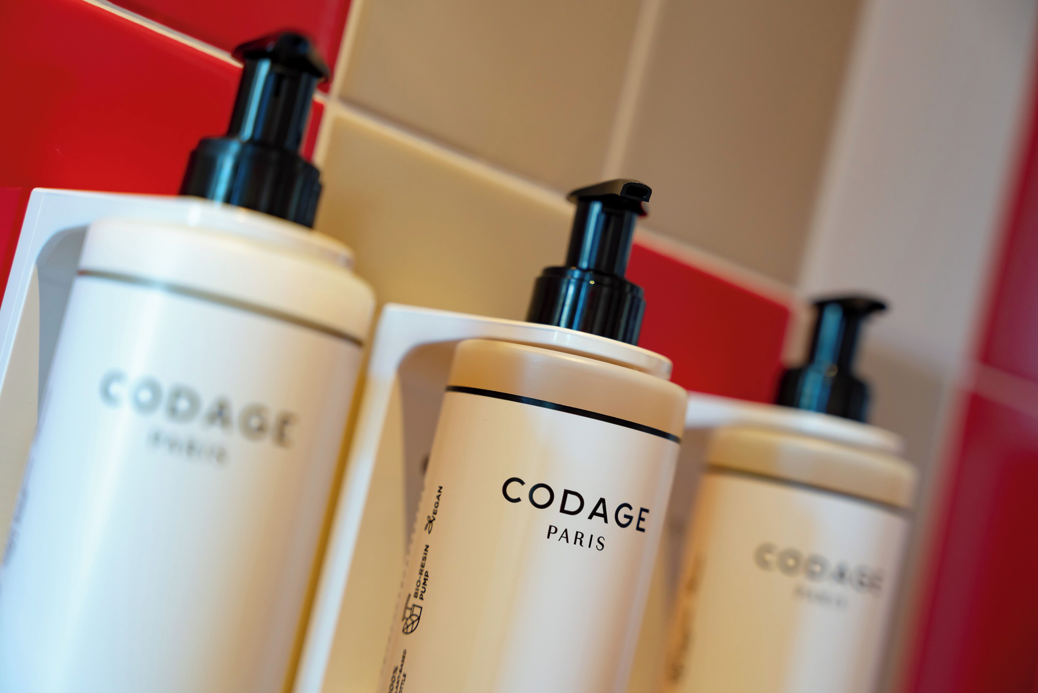 Tres botellas de productos para el cuidado de la piel CODAGE Paris con dosificadores.