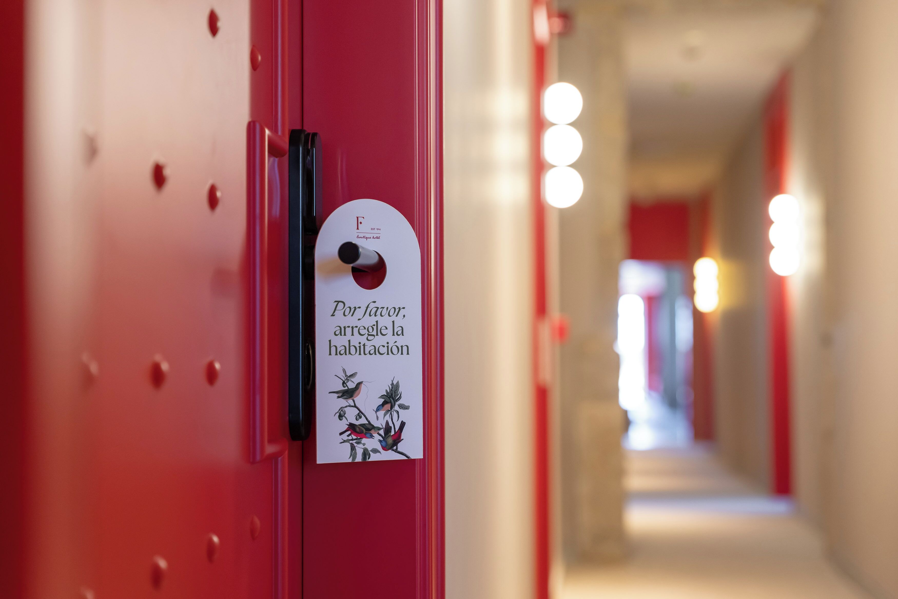 Una puerta roja con un letrero solicitando a los huéspedes coordinar su alojamiento.