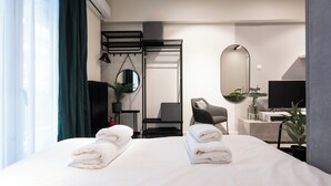 A modern hotel room with a neatly made bed, a desk with a computer, a chair, a TV, and a large mirror. - Modern Studio, Walking distance to Kolonaki & The Ilisian (Athens)