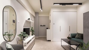 A modern living room with a grey sofa, a coffee table, and a grey armchair. There is a large mirror on the wall, a potted plant, and a white cabinet. - Modern Studio, Walking distance to Kolonaki & The Ilisian (Athens)