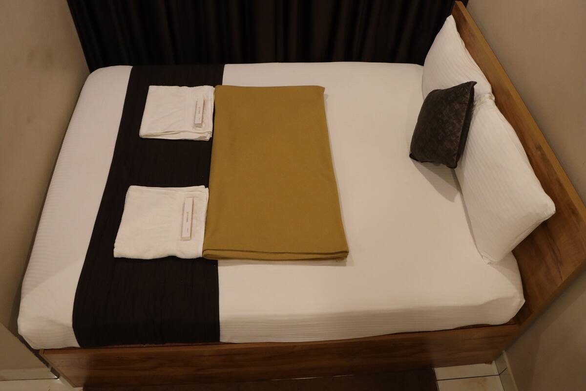 A neatly made bed with a brown blanket, white pillows, and a dark headboard.