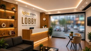 A modern lobby with a reception desk, seating area, and a large window offering a view of the city. - Igloo Stay Edachira (Kanayannur)