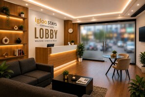 A modern lobby with a reception desk, seating area, and a large window offering a view of the city. - Igloo Stay Edachira (Kanayannur)