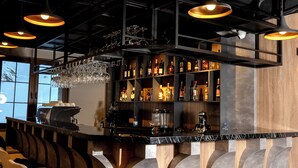 A bar area with shelves of liquor bottles, a coffee machine, and a wine glass chandelier. - KAF MOUNT ERCİYES (Hacilar)