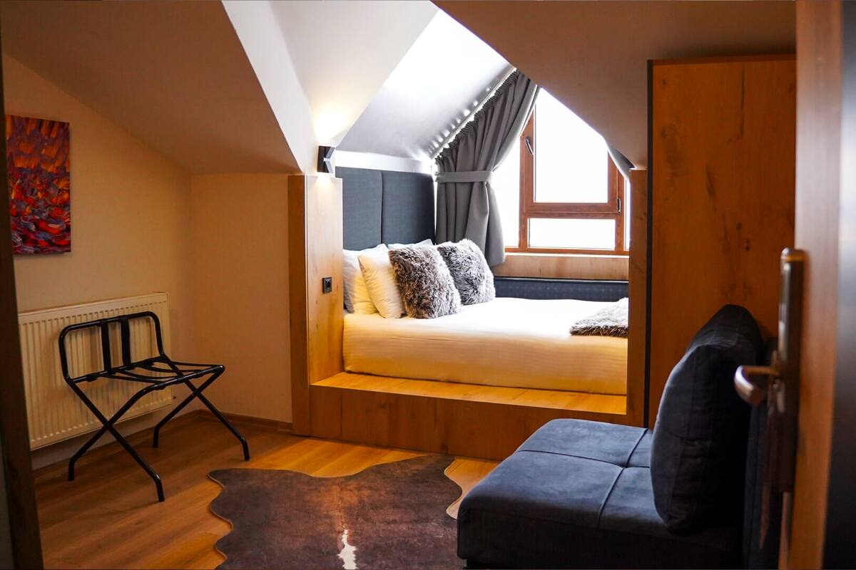 Quarto estilo loft com cama, uma cadeira e um radiador.