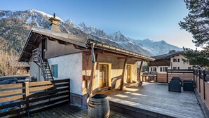 Ein rustikales Chalet mit Holzterrasse, Fass und Bergblick.