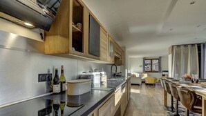 Eine moderne Küche mit Edelstahlgeräten, Holzschränken und einer Essecke mit Barhocker.