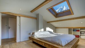 Ein Schlafzimmer mit einem Holzbett, einem Oberlicht und Blick auf Berge.
