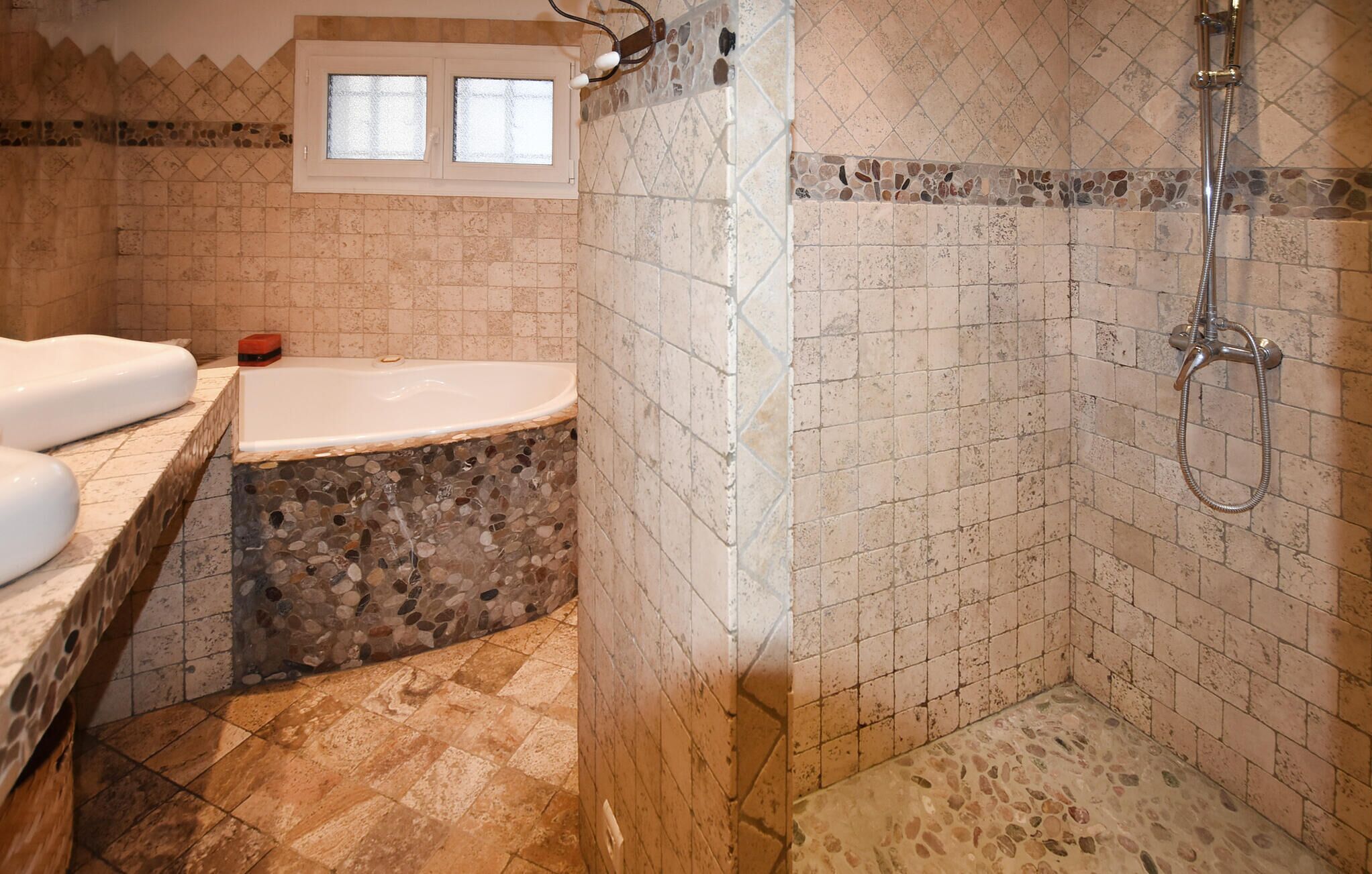 A bathroom with a bathtub, shower, and mosaic tile walls.