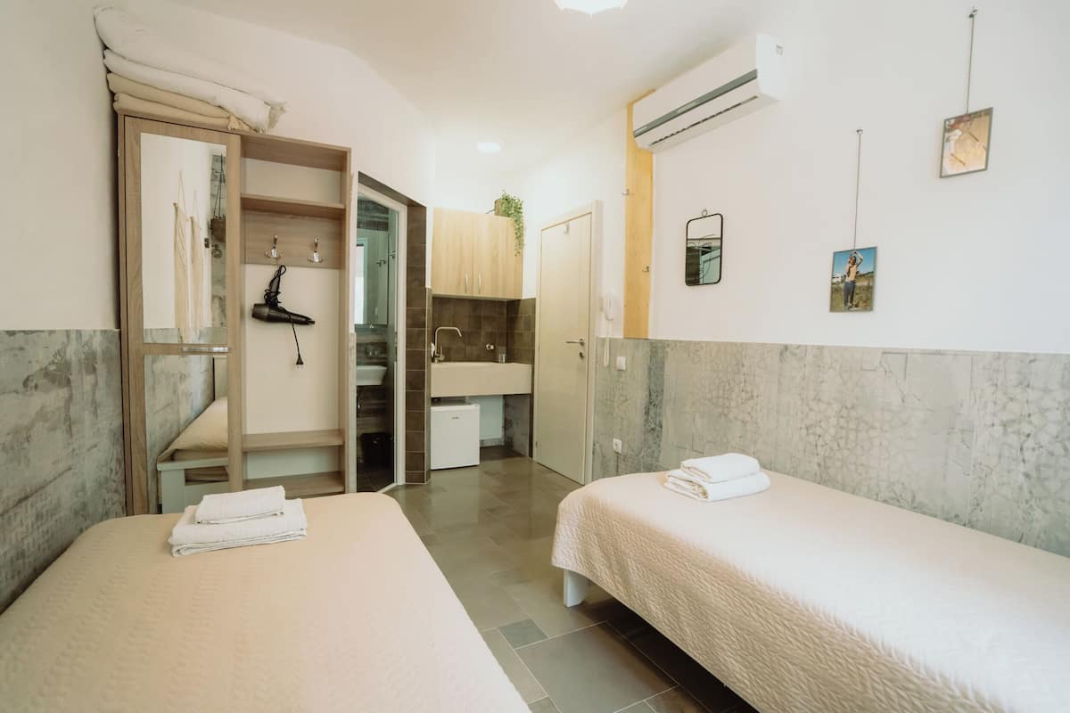 A hotel room with two beds, a bathroom, and a small kitchenette.