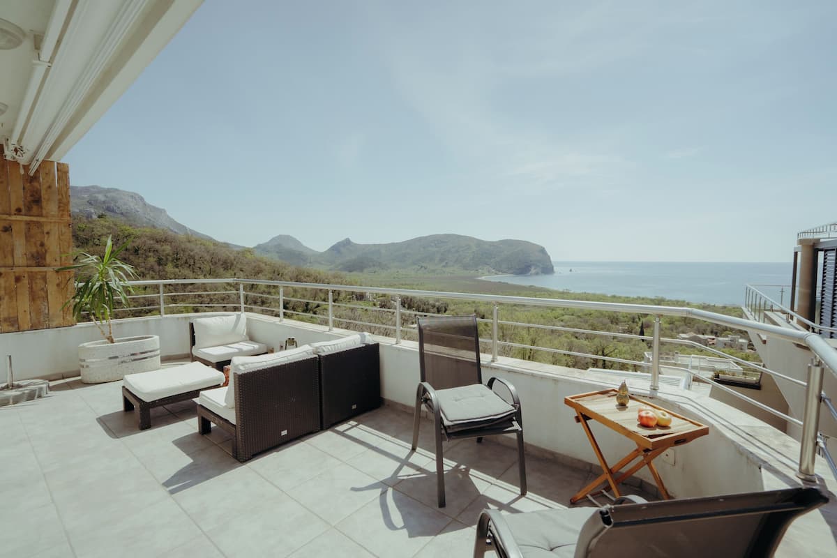 A balcony with a sofa, chairs, and a table with fruits.