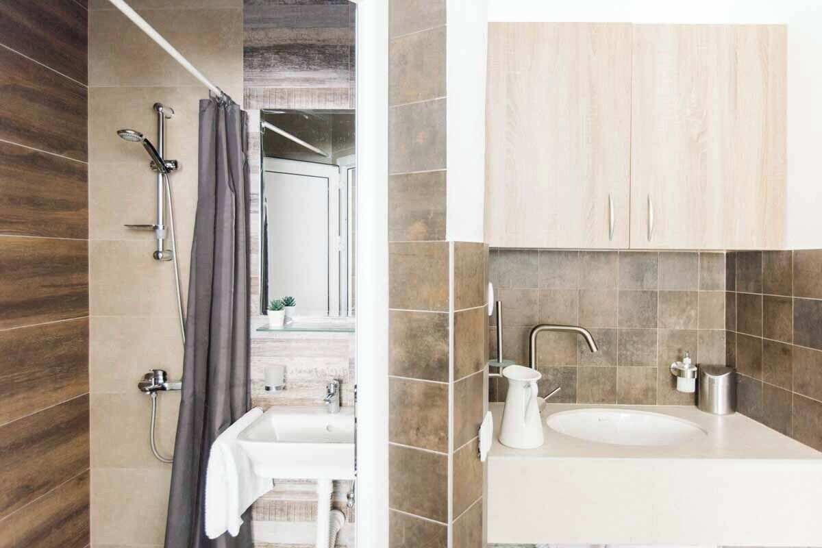 Een moderne badkamer met een douche, wastafel en spiegel.