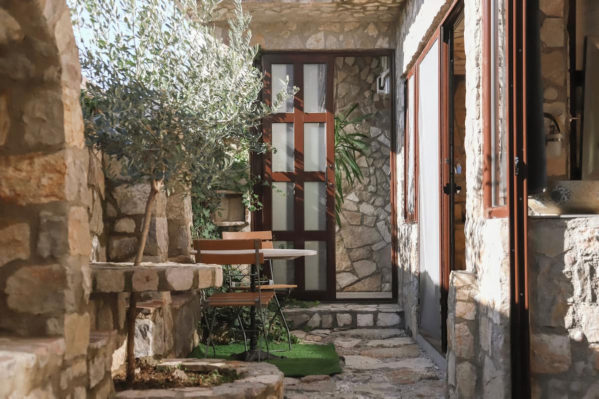 A stone-walled courtyard with a wooden door, a small table, and a bench.