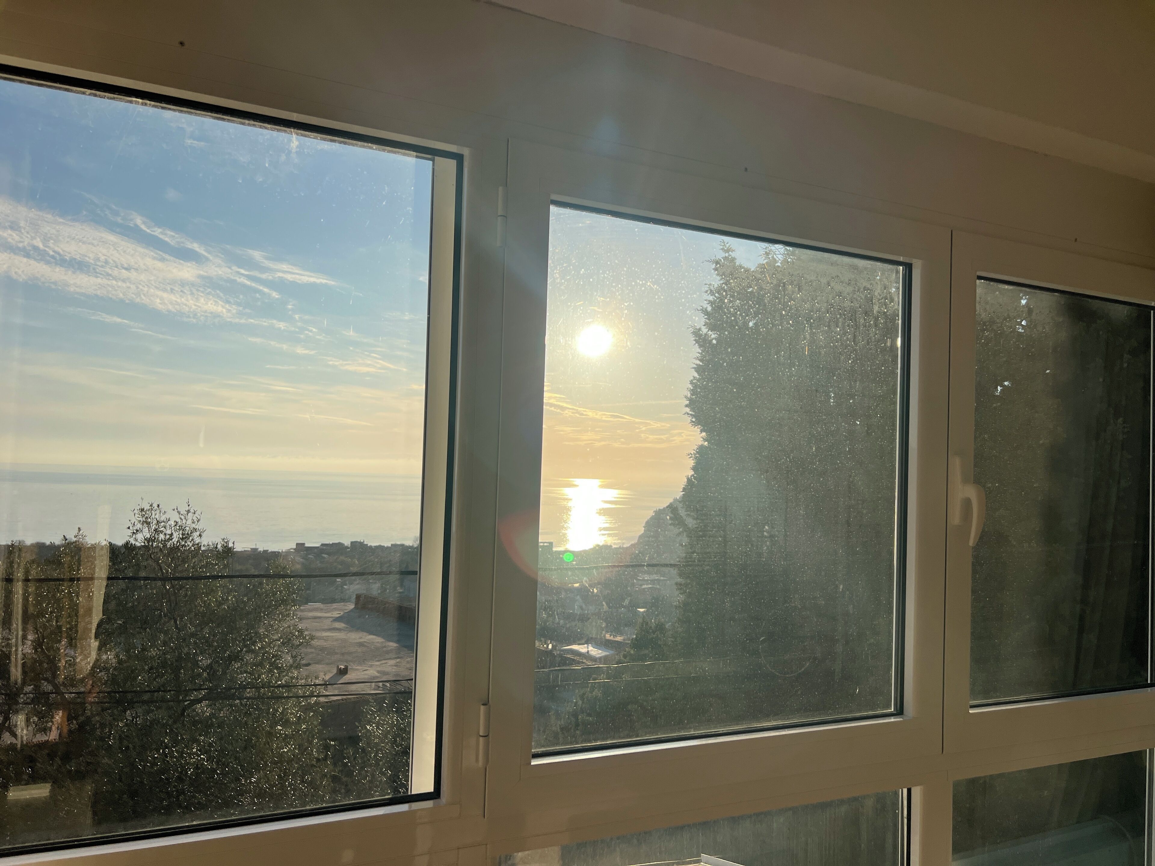 A room with large windows offering a view of the sunset over a cityscape.