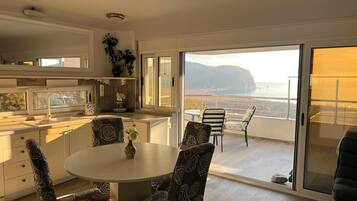Cocina moderna con comedor, puertas de vidrio correderas que dan a un balcón con vistas al mar.