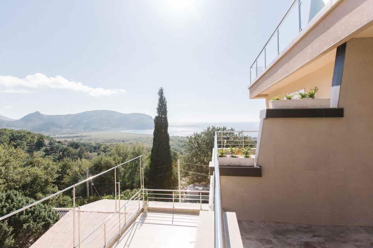 A modern building with a balcony overlooking a mountainous landscape.