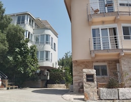 Un edificio residencial de varios pisos con fachada curva, balcones y base de piedra.