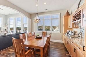 A spacious kitchen with a dining area, large windows, and wooden cabinetry.