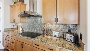 A kitchen with granite countertops, wooden cabinets, a stainless steel range hood, a toaster, and a coffee maker. - Penthouse Paradise at Delton Grand (Wisconsin Dells)