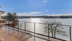 Een balkon met uitzicht op een bevroren meer, een metalen hekwerk en een heldere lucht.
