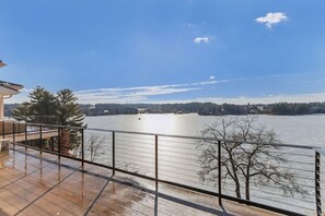 Un balcone con vista su un lago ghiacciato, una ringhiera in metallo e un cielo sereno.