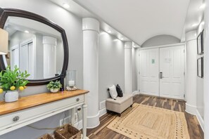 Un pasillo moderno con una consola de madera, un espejo, un banco y un espejo grande.