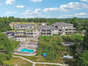 A multi-story hotel with a swimming pool and a landscaped garden.