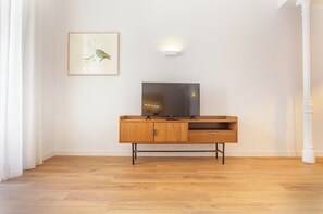 A room with a wooden floor, a TV on a wooden cabinet, and a framed picture on the wall. - Elegant 4-Bedroom Apartment in the Heart of Madrid (Madrid)