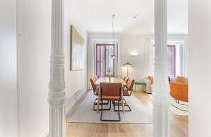 A dining area with a wooden table and chairs, a sofa, and a lamp. - Elegant 4-Bedroom Apartment in the Heart of Madrid (Madrid)