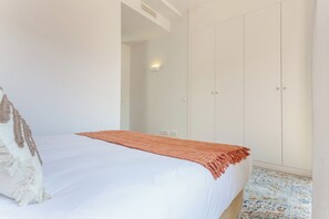 Ein Schlafzimmer mit einem Bett, einem Kleiderschrank und einem gemusterten Teppich.