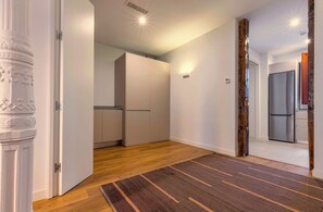 Ein modernes Interieur mit Holzboden, einem Streifenmuster-Teppich und einer Küchenzeile mit Schränken und einem Kühlschrank.