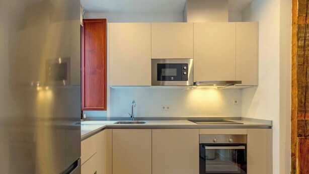 Una cocina moderna con electrodomésticos de acero inoxidable, horno empotrado y microondas.