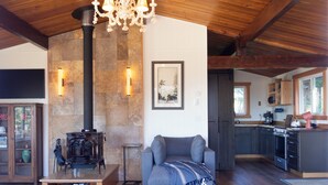 Una sala de estar acogedora con chimenea, un sofá y una cocina visible al fondo.