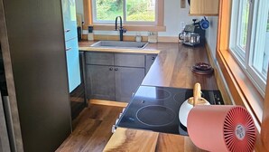 Cocina compacta con techo de madera, estufa integrada, lavamanos y ventana que proporciona luz natural.