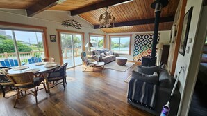 Amplia sala de estar con piso de madera, chimenea y ventana grande con vista a una terraza.