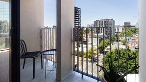 Un balcon offrant une vue sur le paysage urbain, avec des bâtiments et des arbres.