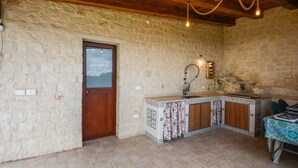 A rustic kitchen with a stone wall, wooden ceiling, and a tiled backsplash. - Stunning home in Noto with house a panoramic view (Noto)