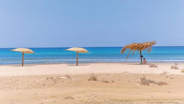 A beach with three thatched umbrellas and a palm tree. - Stunning home in Noto with house a panoramic view (Noto)