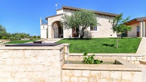 A stone building with a flat roof, a small garden with a tree, and a stone bench. - Stunning home in Noto with house a panoramic view (Noto)