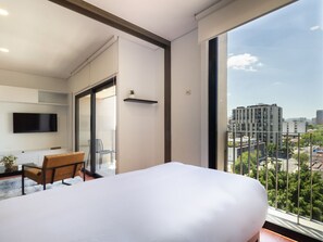 A modern hotel room with a large bed, a desk, and a TV mounted on the wall. - Diseño y confort en Chapultepec 67 (Guadalajara)
