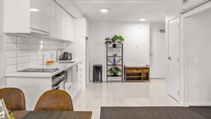 Una cocina moderna con armarios blancos, un lavamanos y un comedor con mesa y sillas.