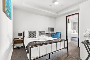 A modern bedroom with a bed, bedside tables, a desk, and a chair.