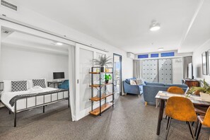 A modern hotel room with a bed, a desk, a sofa, and a dining area. - 2BR Apt w/ Parking in Prime Spot by Zodiak Stays (Auckland)
