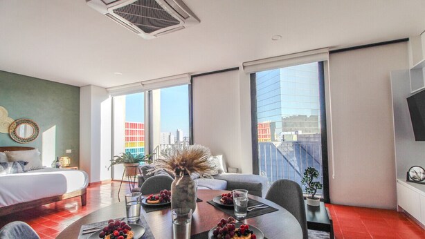 A modern hotel room with a dining area, a bed, and a view of a cityscape. - Departamento exclusivo en Chapultepec 67 (Guadalajara)