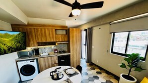 A compact living space with a dining area, kitchen, and a large window offering a city view. - Elegante loft urbano (Guadalajara)