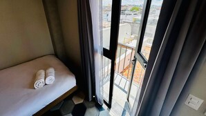 A compact hotel room with a bed, a small table, and a view of the city through a large window. - Elegante loft urbano (Guadalajara)