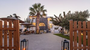 A courtyard with a stone archway, wooden gates, and lanterns. - Santorini Garden Homes (Santorini)